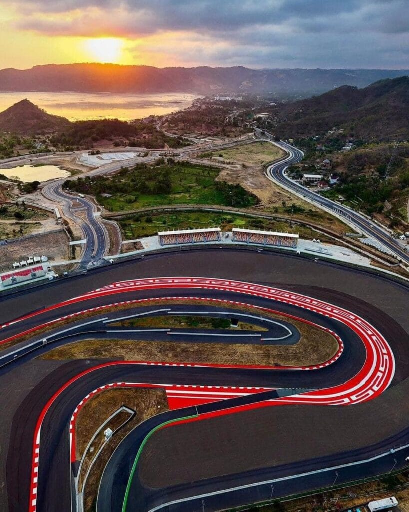 Pemandangan aerial Sirkuit Mandalika Lombok saat sunset, memperlihatkan keindahan lintasan balap, bukit, dan laut dari ketinggian.