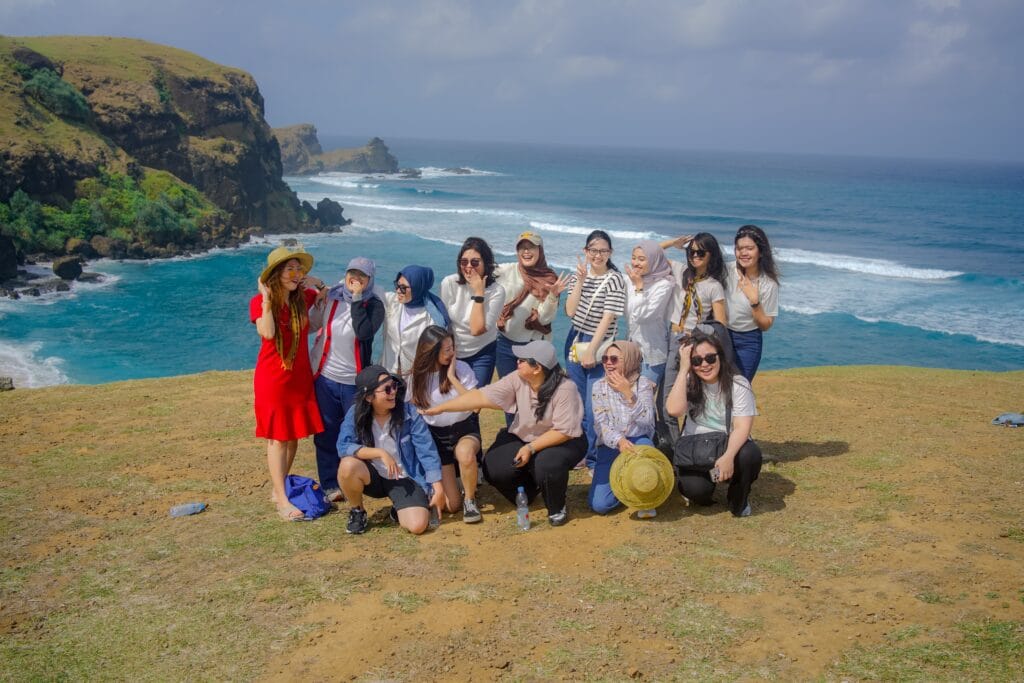 Grup wisatawan Lombok Travelution berpose ceria di puncak Bukit Merese Mandalika dengan latar belakang pemandangan laut biru yang indah.