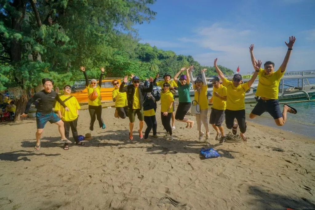 Grup wisata perusahaan menikmati kegiatan team building di pantai Lombok dengan ekspresi ceria dan semangat.