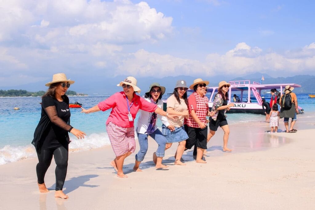 Grup wisatawan wanita berpose ceria di pantai pasir putih saat mengikuti Paket Wisata Lombok 3D2N Gili Nanggu dan Pink Beach