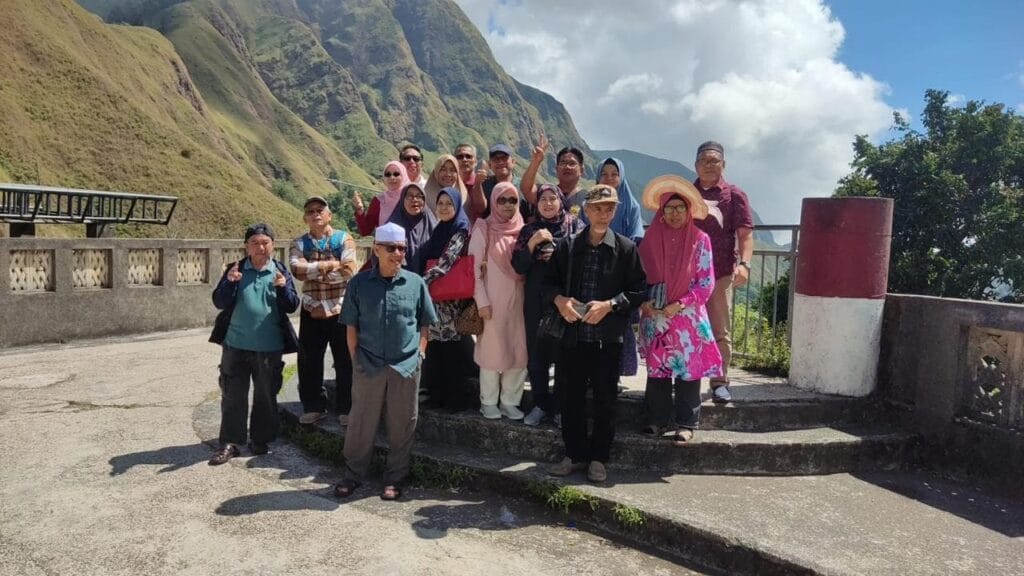Sebuah rombongan wisatawan berfoto bersama di sebuah viewpoint dengan latar belakang pemandangan pegunungan yang megah di Sembalun, Lombok.