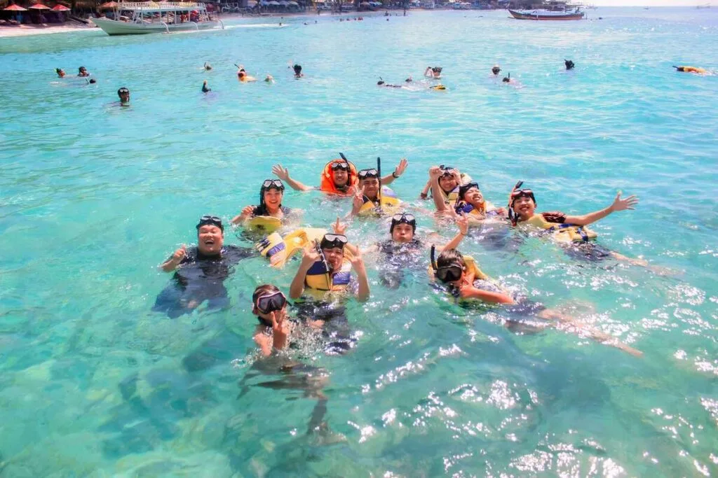 Sekelompok wisatawan ceria snorkeling di perairan jernih Gili Nanggu dalam paket wisata Lombok.