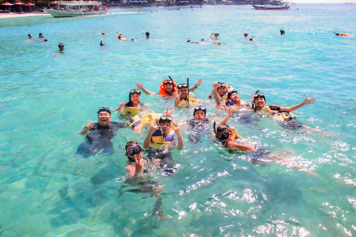 Sekelompok wisatawan ceria snorkeling di perairan jernih Gili Nanggu dalam paket wisata Lombok.