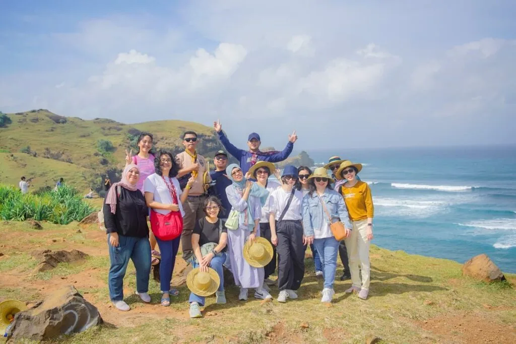 Sekelompok wisatawan berpose bersama di puncak Bukit Merese dengan latar belakang pemandangan Samudra Hindia di Lombok Selatan.