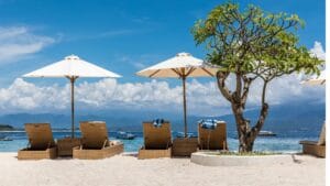 Pemandangan pantai indah di Gili Trawangan Lombok dengan kursi santai dan payung putih di tepi laut