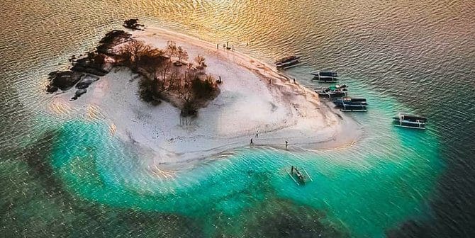 Pemandangan Gili Kedis, pulau kecil berpasir putih dengan pepohonan rindang dan air laut biru jernih.