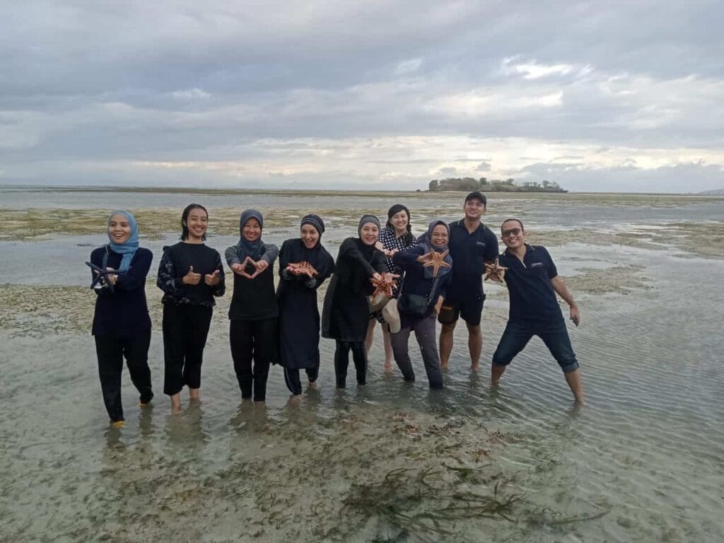Peserta pakej percutian Lombok bergambar di Gili Pasir sambil memegang bintang laut.