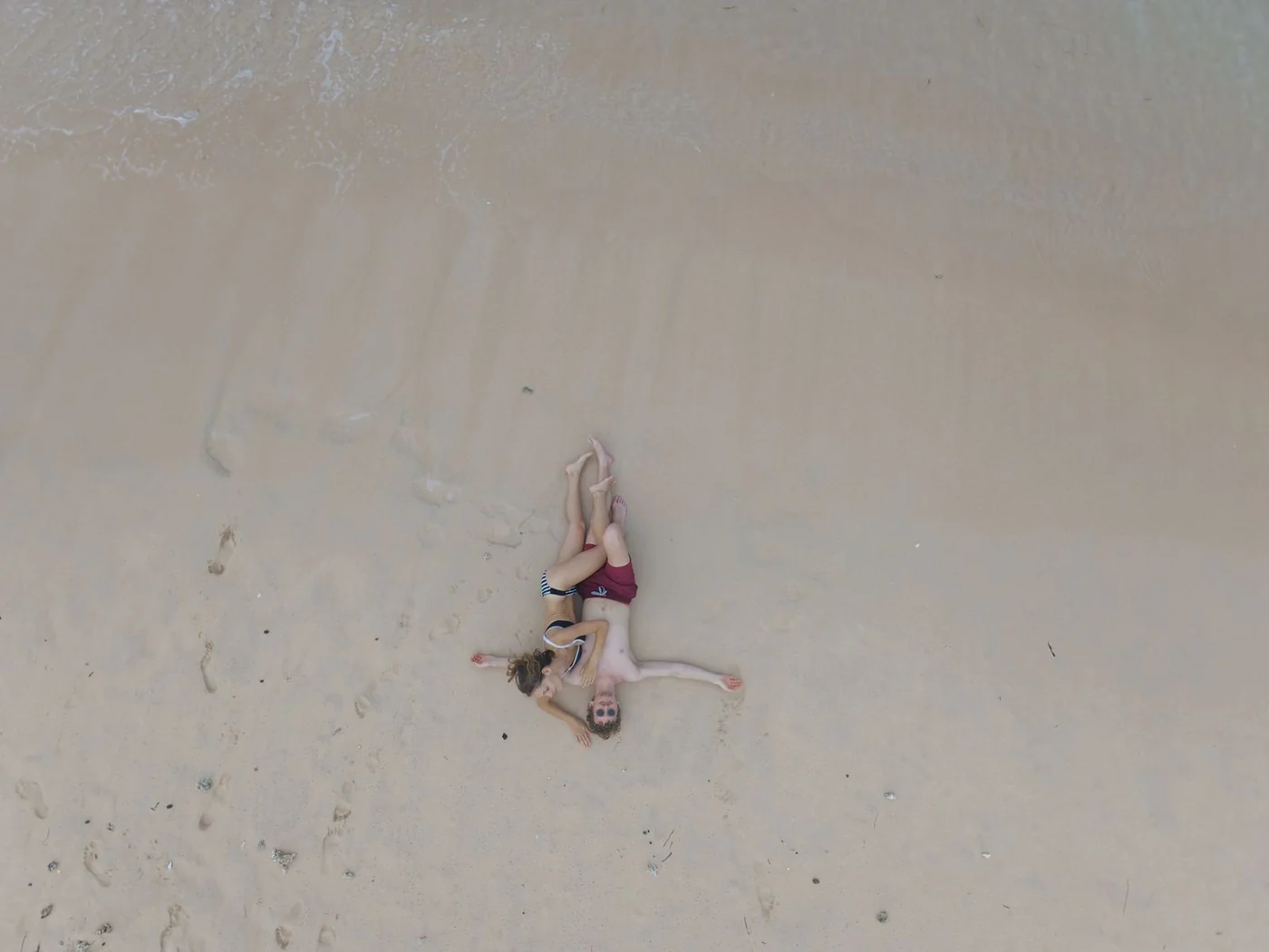 Aerial view of a couple on an empty stretch of white sand in Lombok
