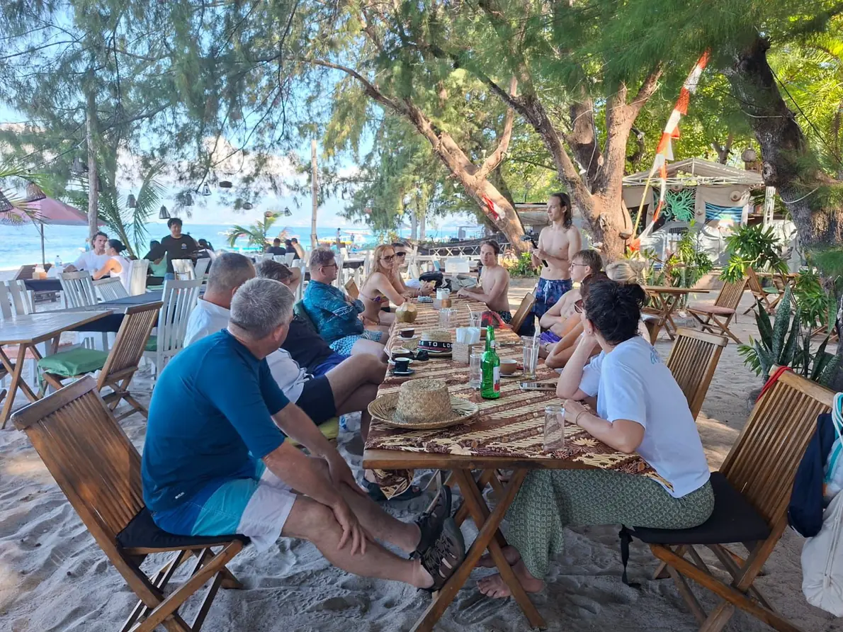 Guests having the included lunch at a table beside the beach on a Lombok tour