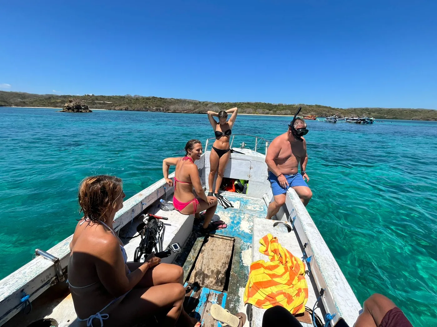 Guests resting on the boat at a snorkelling stop over clear turquoise water in Lombok